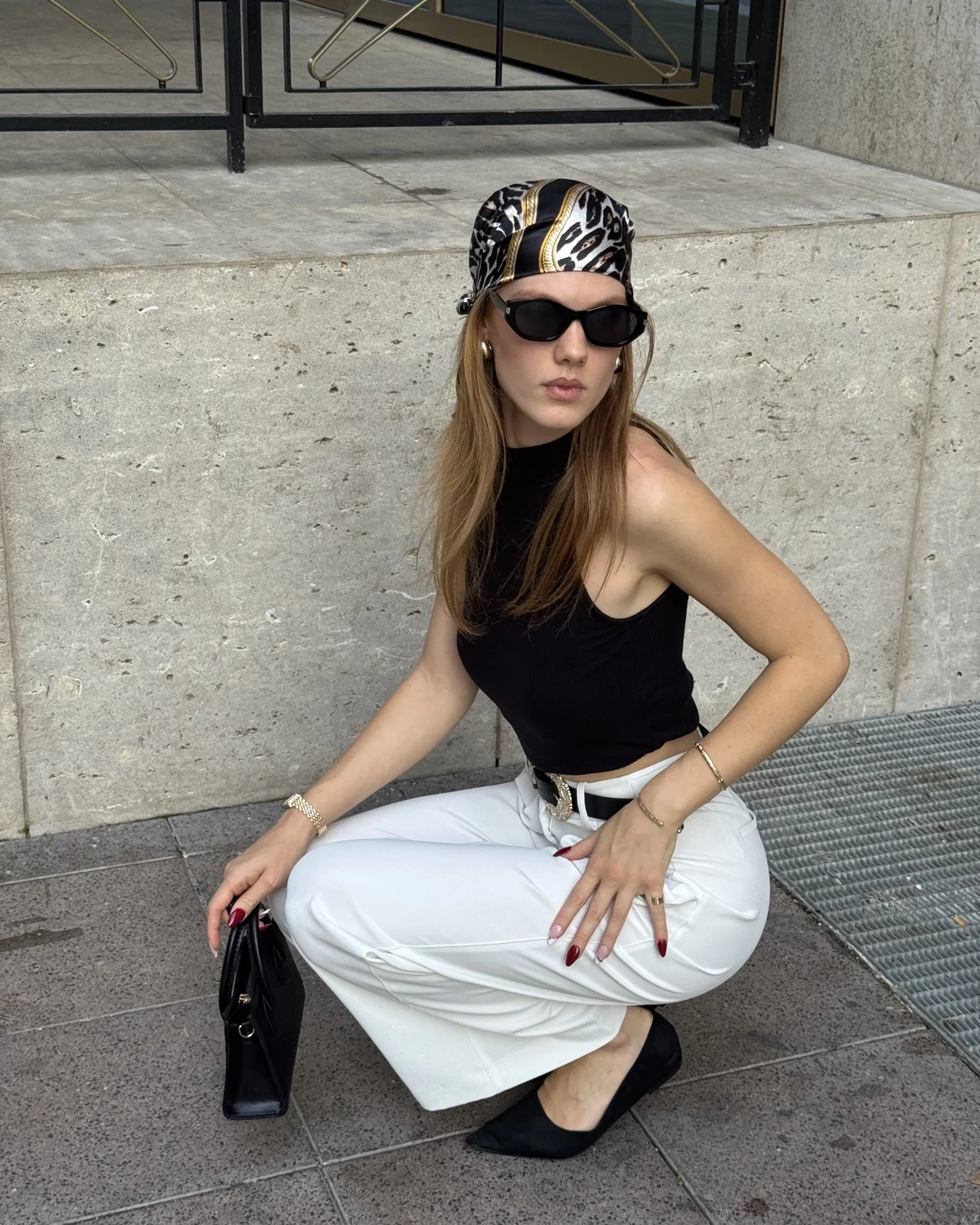 Stella wearing a headscarf and a black top, seated outside