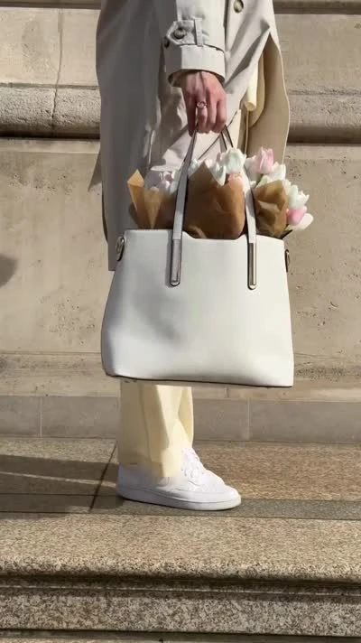 Stella carrying tulips and a handbag on stone steps